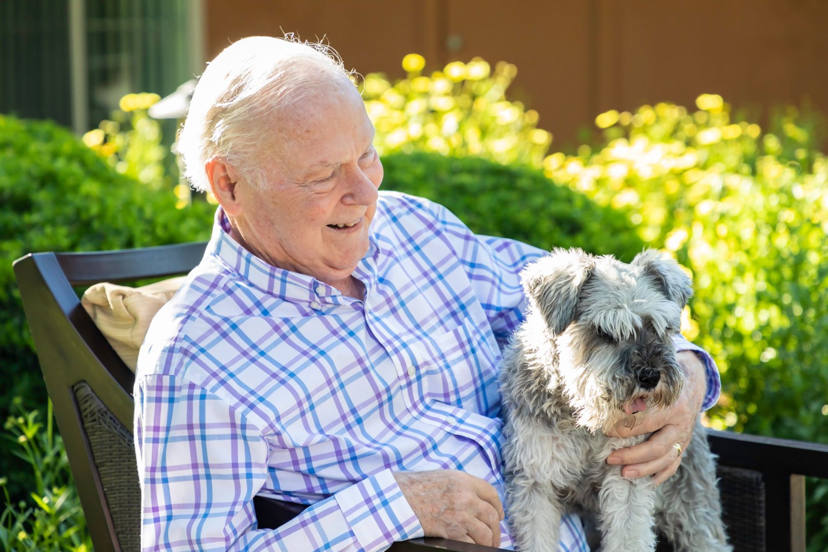 Senior man sitting outside with a small dog on his lap